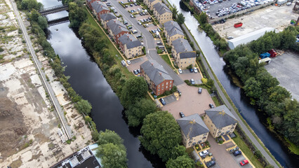 Aerial photo a modern housing estate next to a canal in the Leeds City Centre in West Yorkshire in the UK, showing the brand new houses with water on either side and construction work being down