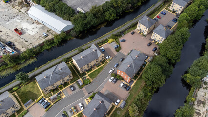 Aerial photo a modern housing estate next to a canal in the Leeds City Centre in West Yorkshire in the UK, showing the brand new houses with water on either side and construction work being down