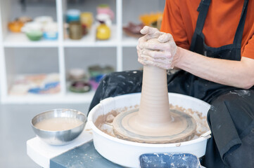 Close-up of a potter's hands working on a pottery wheel. 