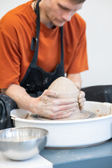 A potter working on a potter's wheel. Vertical photo.