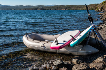 Rubber boat with two SUP boards on a rocky seashore