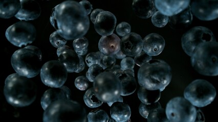 Fresh pieces of blueberries falling into water, top down view, black background