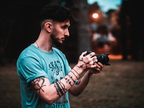 Young Man with Camera Lens in Urban Park During Late Afternoon