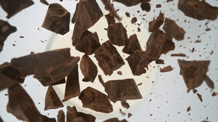 Tasty chocolate chunks falling into cream, top down view