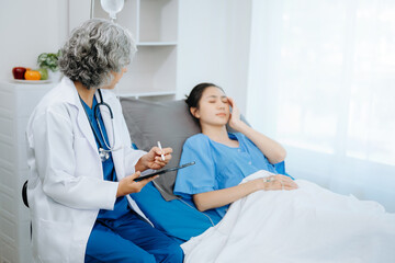 Obraz premium Doctor and young Female patient who lie on the bed while checking pulse, consult and explain with nurse taking note .