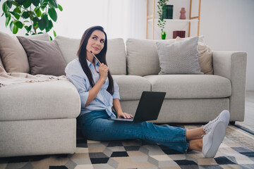 Obraz premium Full length portrait of pretty lady sit floor use laptop think wear shirt bright interior apartment indoors
