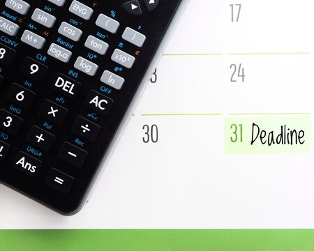 Due date concept: a calendar showing the text Deadline on the 31st and a black calculator. Cutoff, closing date or final date background