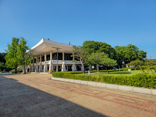 A large building with a white roof and a green roof. The building is surrounded by a brick walkway and a green lawn