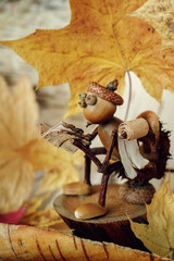 A handmade gnome made of acorns sitting on the toilet and reading a book. The mood of autumn depression and quiet time. Vertical photo