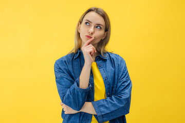 Pensive suspicious attractive woman looking for answers on her questions isolated on yellow...