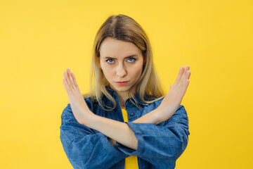 Stop. Concerned woman showing refusal sign, saying no over yellow background