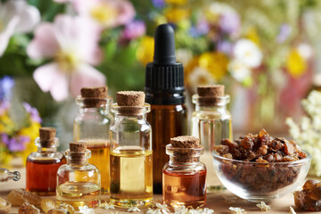 Bottles of aromatherapy essential oil with myrrh, frankincense and spring flowers