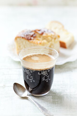 Coffee with frothed milk and sliced ​​yeast cake in the background. Copy space.