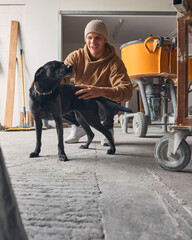 Smiling Male Worker With Pet Dog In Concrete Workshop 