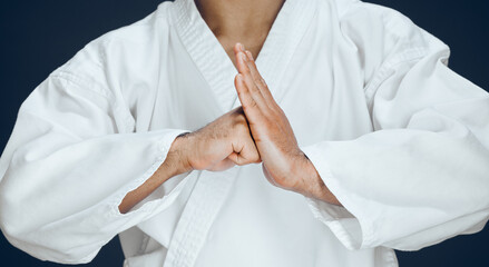 Man, hands and karate form in studio, fighter and ready for training or practice on dark background. Male person, athlete and warrior in dojo for martial arts, respect gesture and welcome to sports