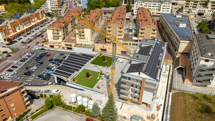 Fototapeta premium Aerial view of industrial tower crane operating in a newly built neighborhood. These large machines allow the concrete plates weight balance.