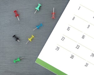 Monthly calendar and unstuck push pins on a table. Tools for marking events on a schedule and a close-up of a planner. Time management concept