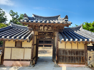 Naklejka premium A building with a large wooden door and a roof with Chinese characters on it. The building appears to be a temple or a shrine