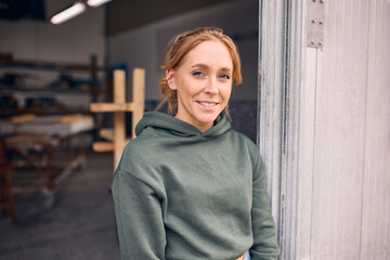Portrait Of Smiling Female Worker Standing In Doorway Of Concrete Workshop 