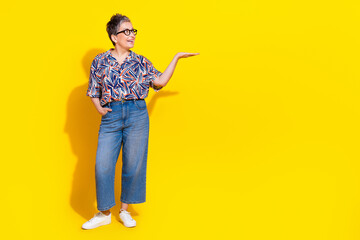 Photo of nice aged lady arm hold empty space wear shirt isolated on yellow color background