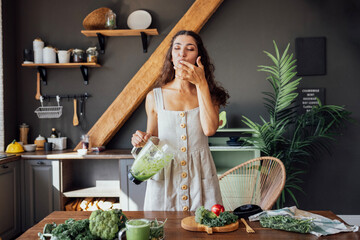 A happy curly-haired girl in a linen sundress is preparing a healthy breakfast