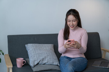 weekend day asian girl is sitting on couch blowing off steam by singing playing guitar at home....