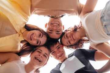 Funny smiling teenagers standing and looking down at camera