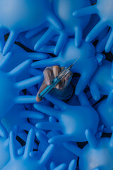 background of inflated blue medical latex gloves, in the center is the hand of a woman in a transparent glove with a syringe