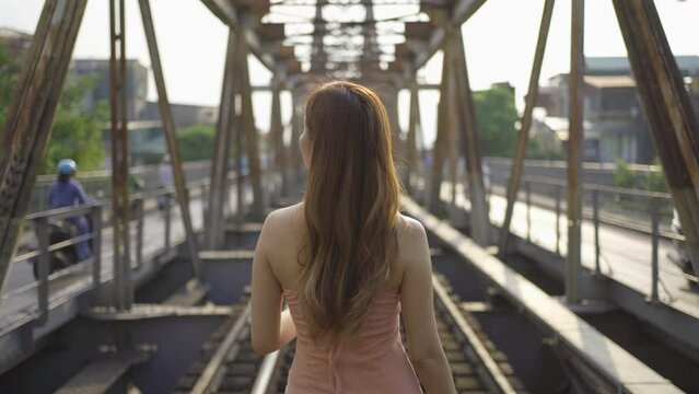 Portrait of Asian Vietnamese fashion woman. Vintage steel train bridge at Long Bien railway through a river in Downtown Hanoi, Vietnam. Urban city town. People lifestyle.