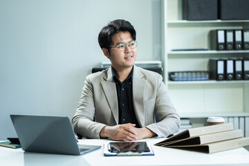Fototapeta premium Young Happy Businessman Using Computer in Modern Office. Manager Smiling, Working on Financial and Marketing Projects. Drinking Coffee from a Mug.