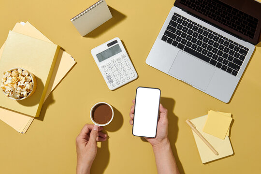Hands using mockup smartphone on workspace with empty screen display.