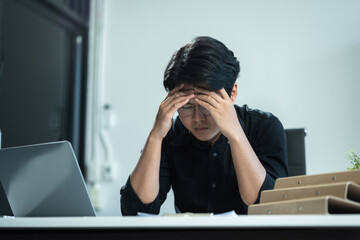 Young stressed Asian businessman working in the office.