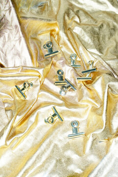 Golden paper clips on a golden shine texture fabric with flashlight