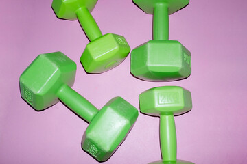 Neon green dumbbells on a pink backgournd with hard direct flashlight