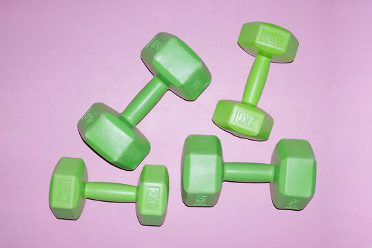 Neon green dumbbells on a pink backgournd with hard direct flashlight