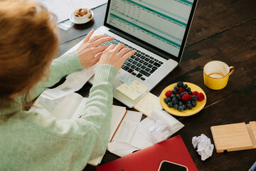 Anonymous woman making monthly budget on laptop