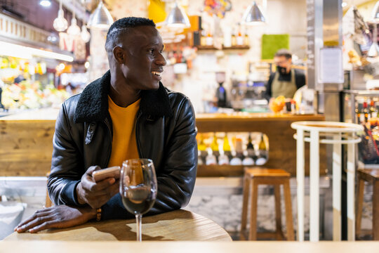 Young man waits for his date while having a glass of wine at a bar