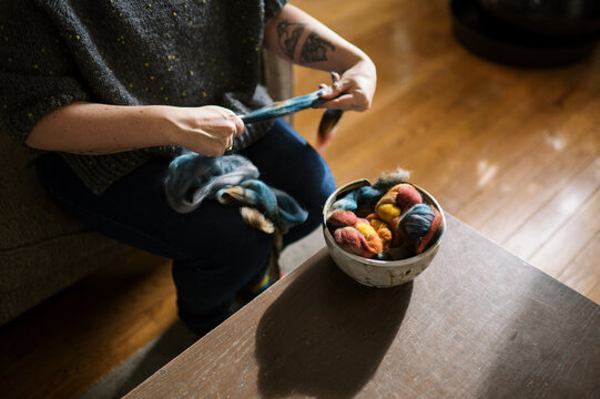 woman prepping colorful roving fiber for spinning