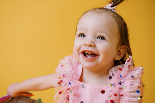 happy baby in dress on yellow backdrop