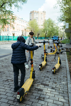 Two People Standing Next to a Row of Scooters