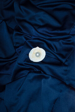 Ocean treasures: seashell and pearl on silk and hard direct flashlight