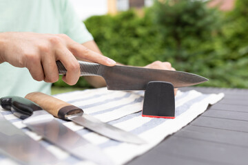 Close-up photo of man sharpening knives with special knife sharpener