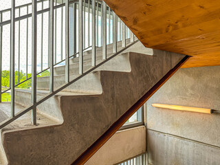 Close-up photo of a modern gray metal railing and concrete stair case between floors.