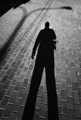 Man's shadow on street pavement tiles backdrop