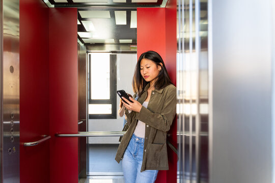 Woman inside elevator using phone