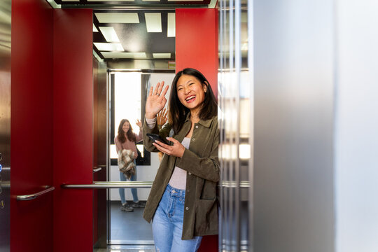 Woman inside elevator using phone