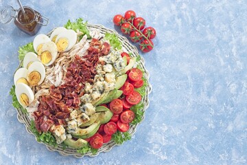 Delicious Cobb salad on a white plate, horizontal top view copy space