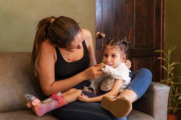 Mother carrying and clothing daughter with special needs at home