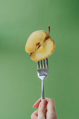 on a green background, a fork in hand with a chopped fermented apple