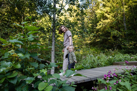 Happy mother and daughter walking along the wooden path outdoors